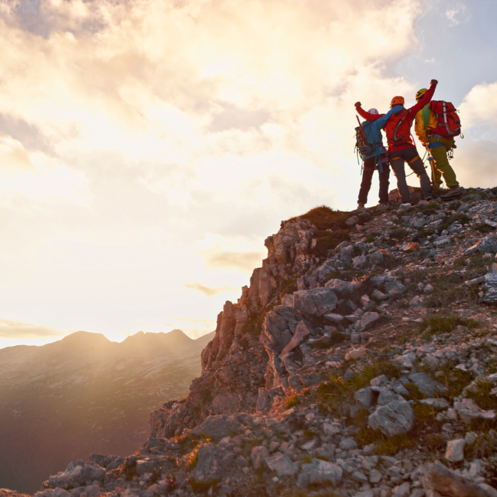 3 people celebrating on top of a mountain