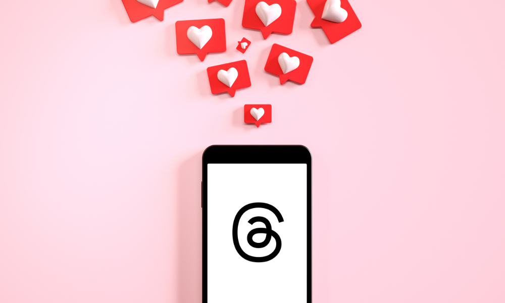 Threads logo on phone with social hearts