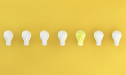 Lightbulbs with one lit on yellow background